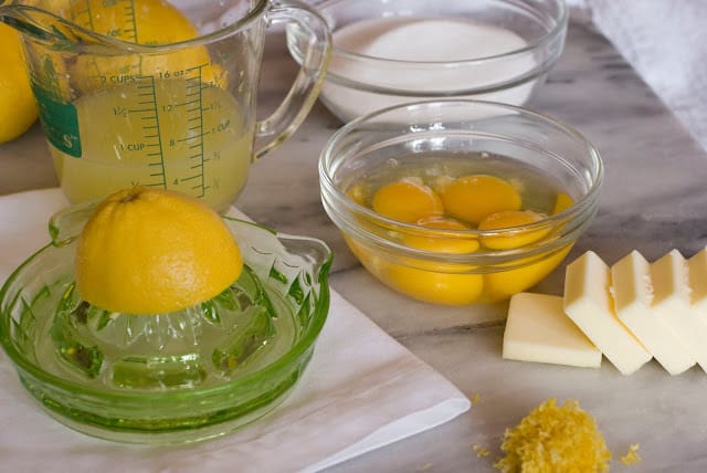 Eggs in a bowl with half a lemon on a juicer and sliced butter