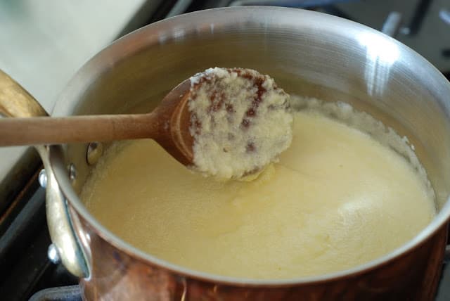 Wooden spoon spoon stirring lemon curd in pot