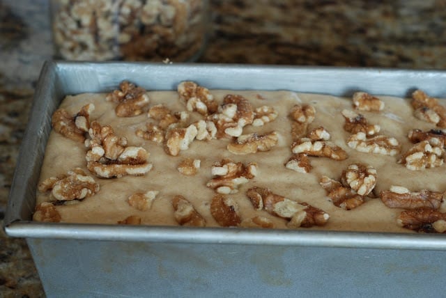 Banana bread batter in loaf pan topped with chopped walnuts