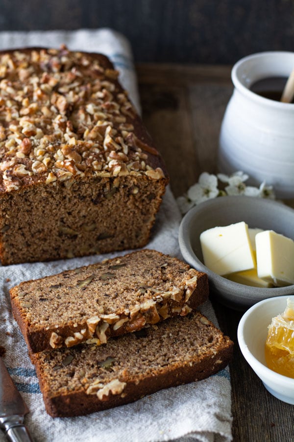 banana nut bread sliced with bowl of butter and honey comb