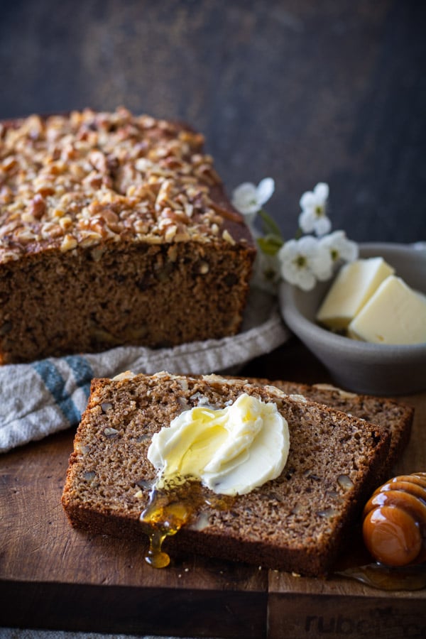 Slice of banana nut bread with spread butter and honey