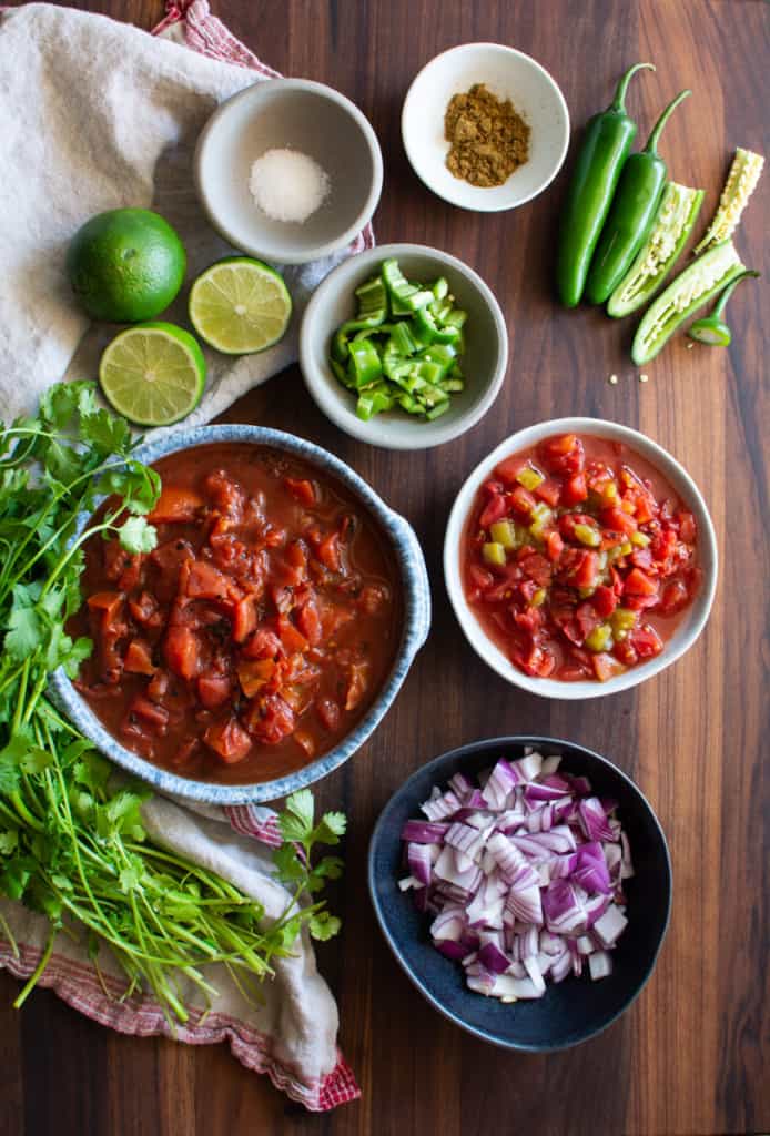 Measured ingredients for fire roasted salsa with canned tomatoes, fire roasted tomatoes, green chiles, limes, serrano chiles, chopped red onion, fresh cilantro. Final image of chipotle salsa recipe.