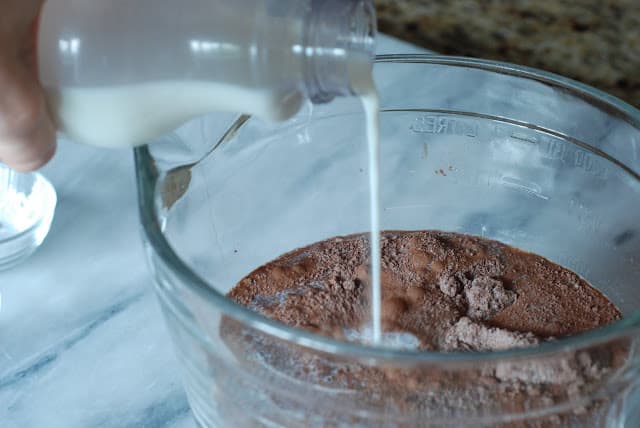 Milk pouring into bowl with cocoa sugar mixture