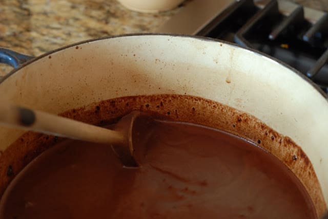 chocolate ice cream custard in pot stirring with wooden spoon