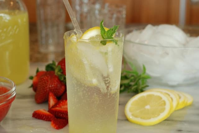 Tall glass of old fashioned lemonade with lemon slices and a sprig of mint leaves