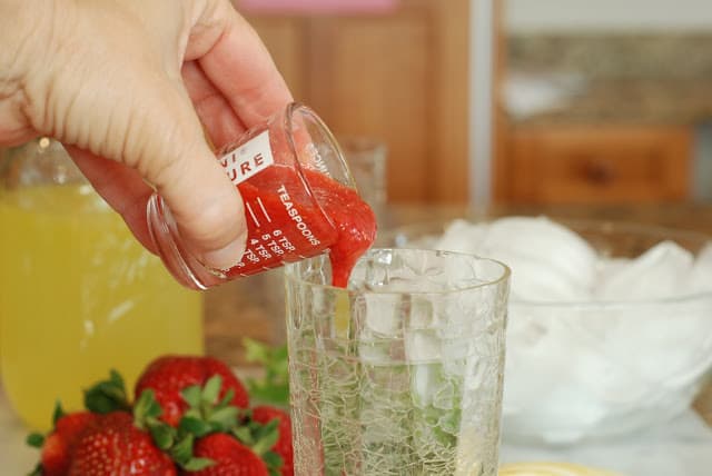 Strawberry puree added to tall glass of lemonade
