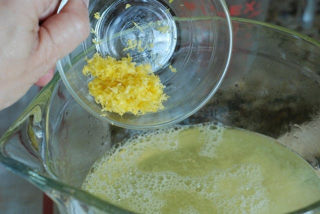 Lemon zest in a small bowl being added to lemonade syrup