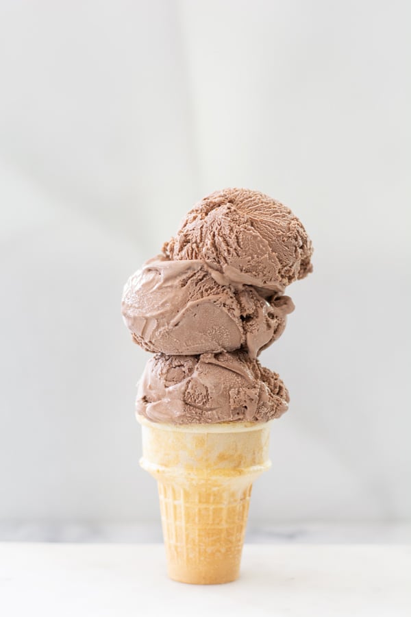 Three scoops of ice cream stacked on a cone.