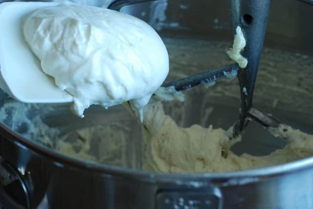 Sour cream added to bowl to make the sugar cookies recipe.