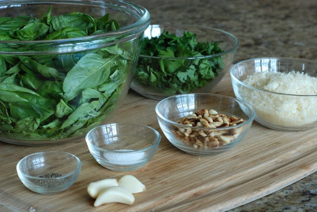 fresh basil, parsley in bowl with pine nuts, garlic, parmesan cheese