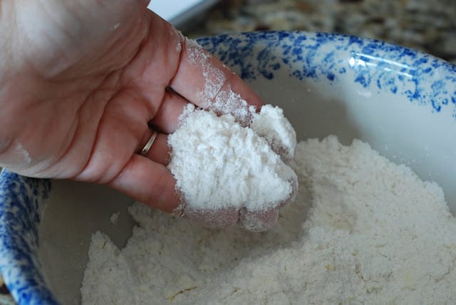 hand with fingers in shortbread mixture tossing in grated butter