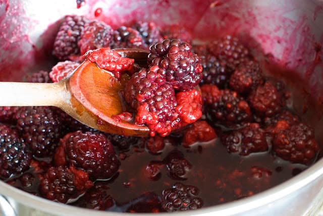 simmer berries in saucepan with wooden spoon