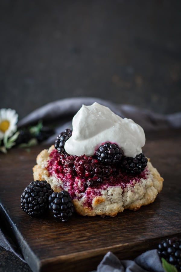 rustic blackberry shortcake on wood board topped with whipped cream