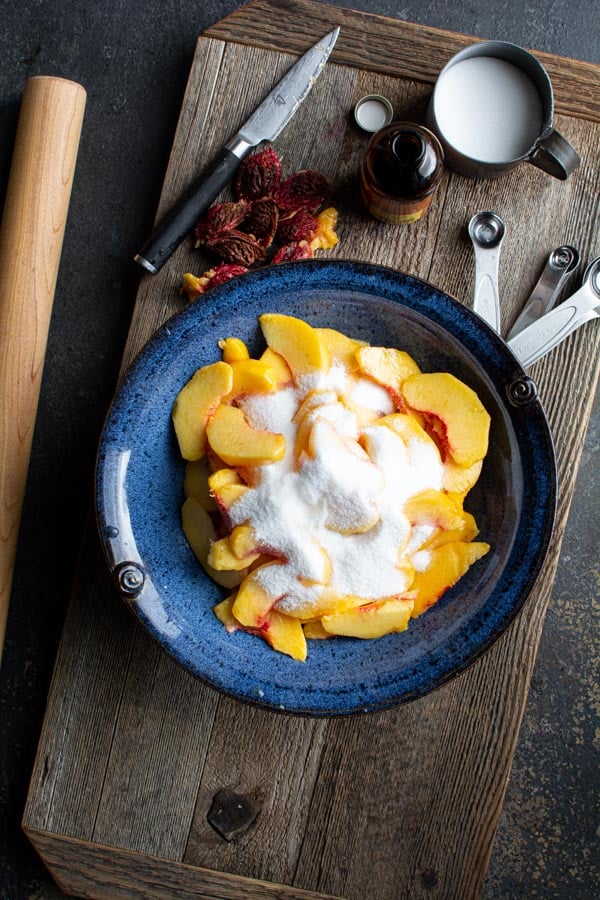 Blue bowl filled with sliced peaches with sugar on top