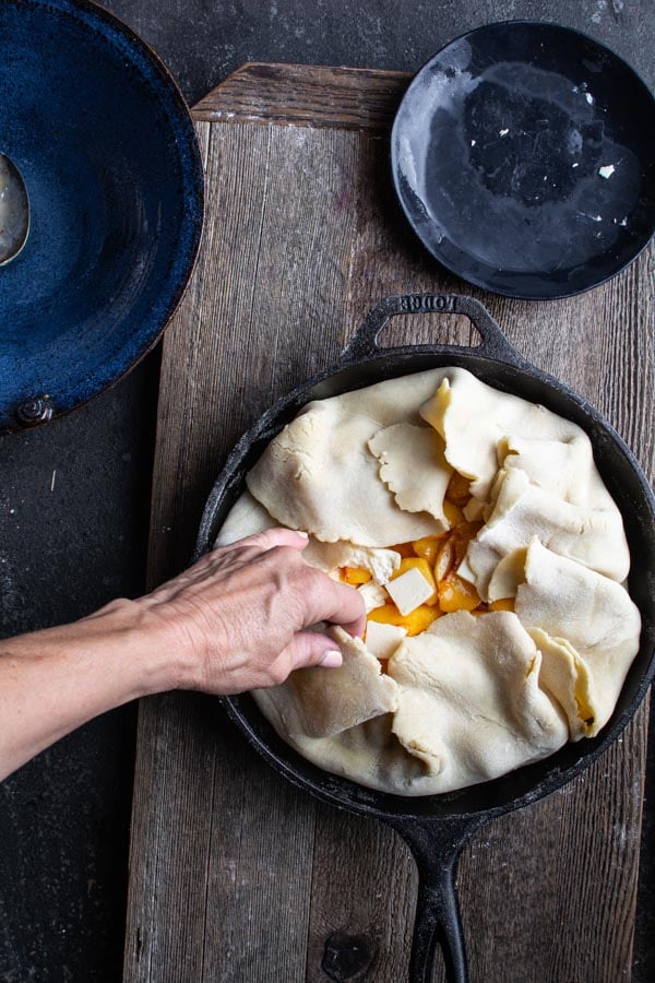 Edges of pie dough folded over top of sliced peaches