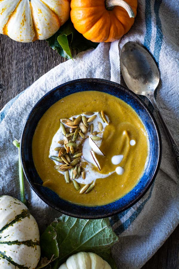 blue bowl with pumpkin soup, drizzle of coconut milk and toasted pumpkin seeds