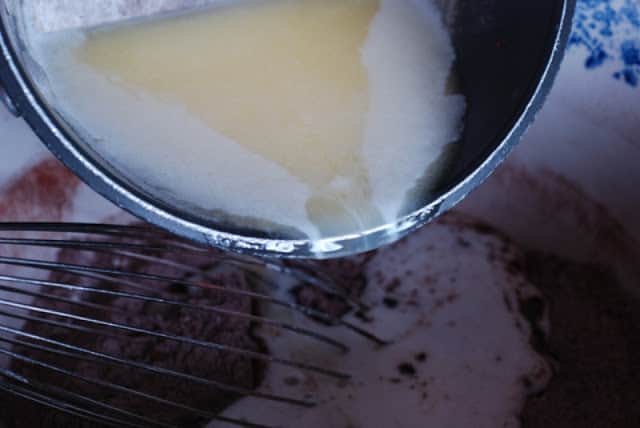 Melted butter pouring from pan into flour mixture
