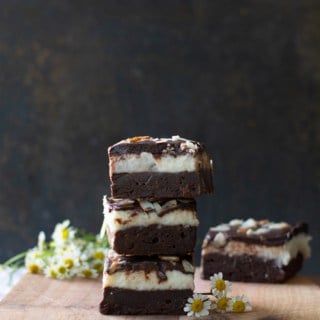 Cut coconut fudge brownies stacked on a cutting board.