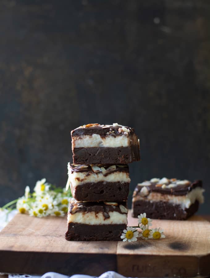 Cut coconut fudge brownies stacked on a cutting board.