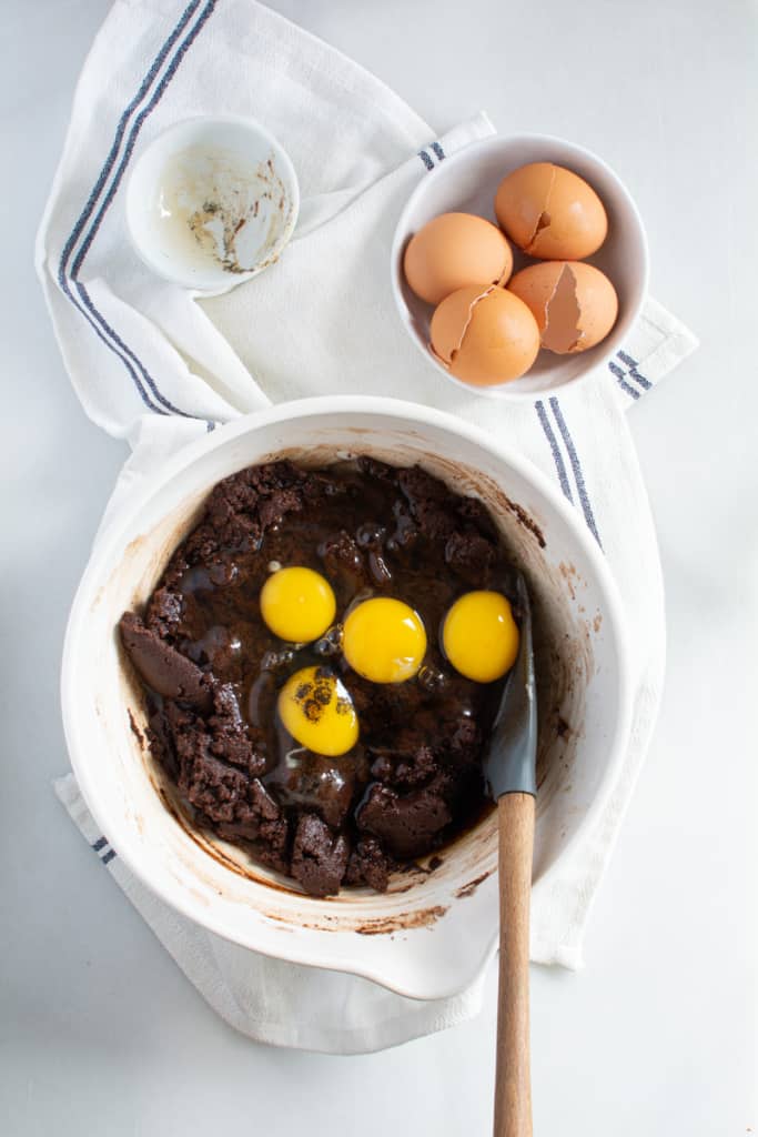 Bowl with mixed brownie mixture with added eggs on top and vanilla.