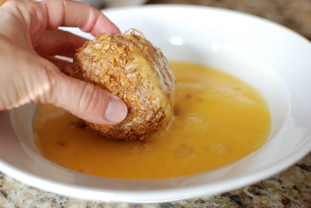 Rolling the frozen vanilla dessert ball in egg.