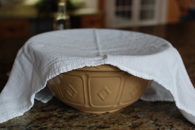 Bowl filled with dough covered with white cloth