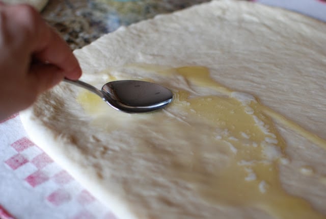 Rolled out dough with melted butter spread with a spoon