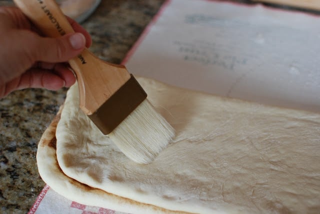 Dough folded over cinnamon sugar side. Pastry brush brushing off excess flour