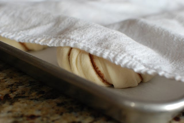 Cinnamon twists on baking sheet covered with cloth that are rising