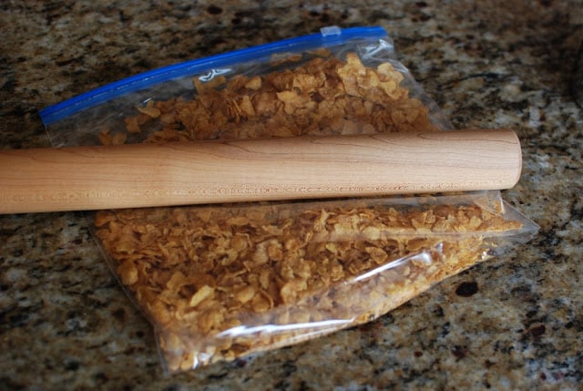 plastic bag filled with cornflakes being crushed with a rolling pin