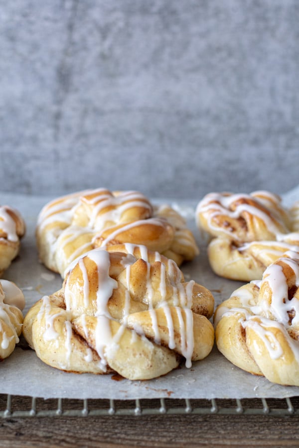 Glazed giant cinnamon twists on parchment with gray back ground