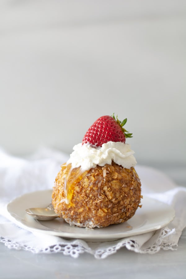 Ice cream rolled in cornflakes, fried, topped with whipped cream and strawberry.