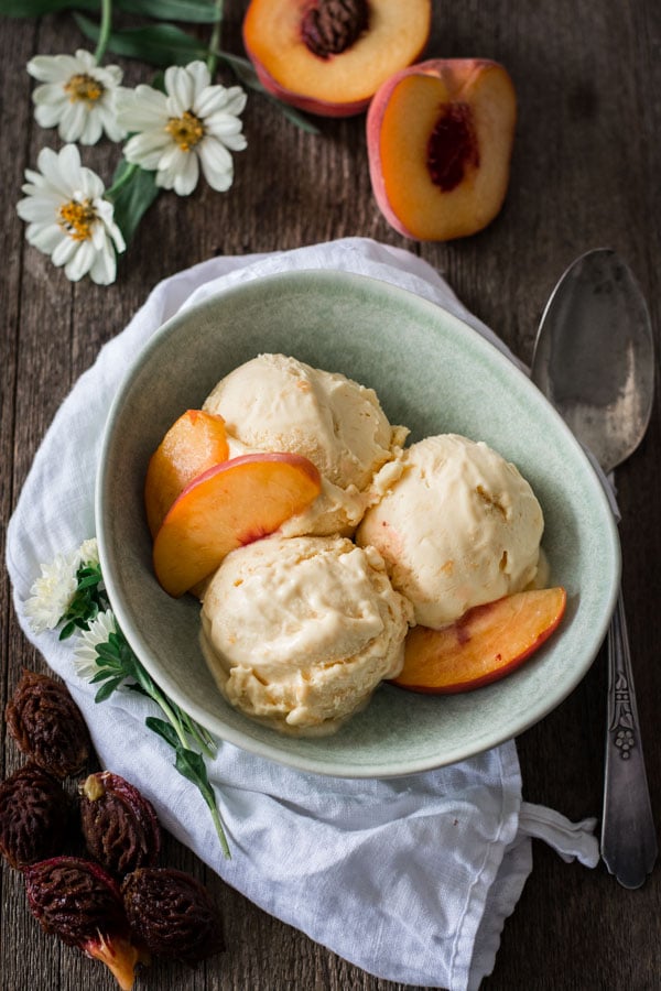 green bowl with peach ice cream and sliced peaches