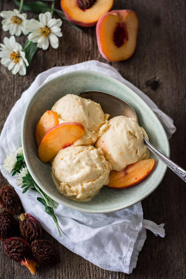 green bowl with peach ice cream and sliced peaches