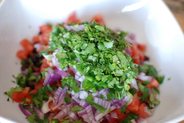 black beans, tomatoes, red onion and cilantro in a white bowl