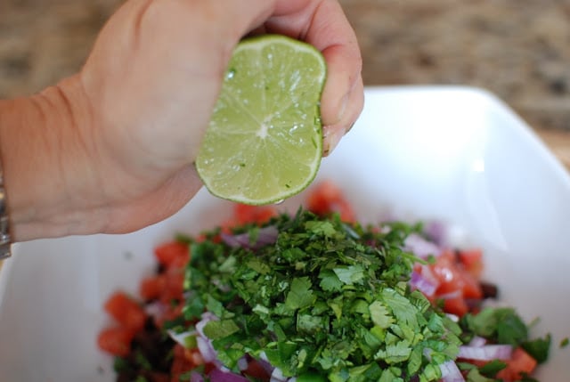 lime squeezing over bowl of bean salsa