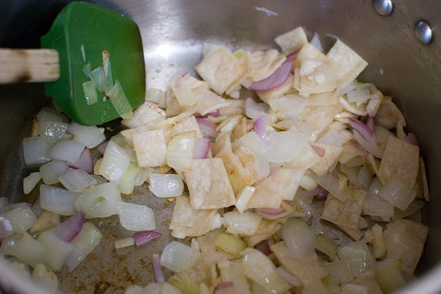 Cut tortillas mixed in with onion and garlic in pot