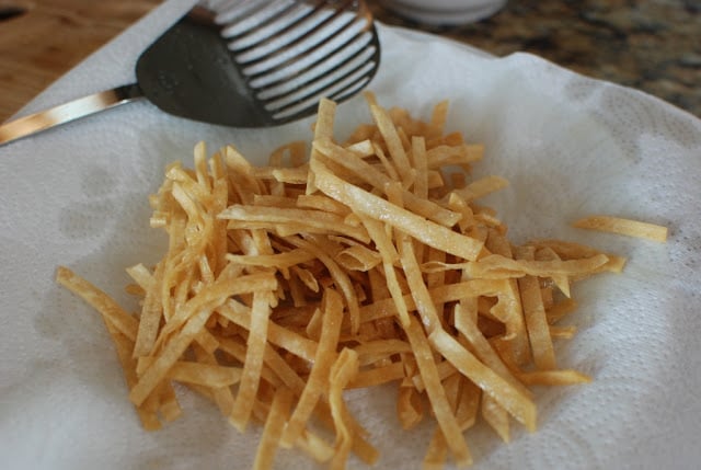 Fried tortilla strips on a paper towel lined plate