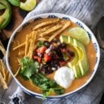 Overhead shot of turkey tortilla soup topped with avocado, black bean salsa, and tortilla strips