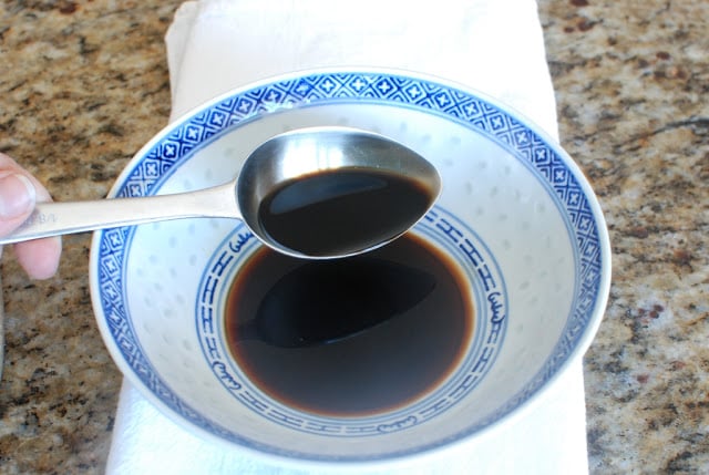 spoonful of soy sauce pouring into bowl