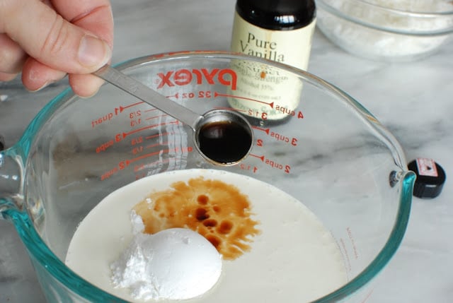 glass bowl with whipping cream, powdered sugar, and vanilla