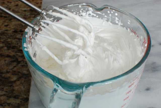 glass bowl with beaters in whipped cream