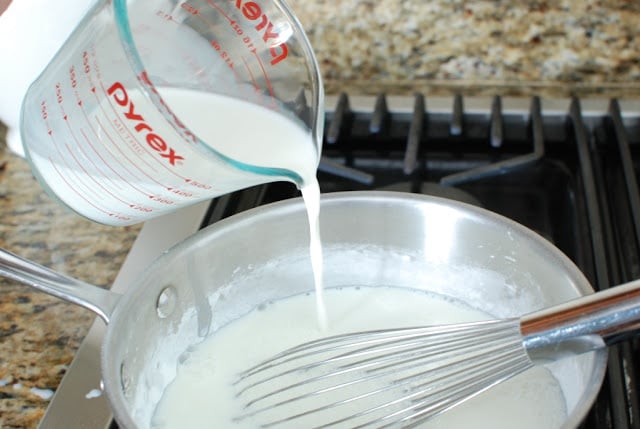 Cream pouring from measuring cup over sugar mixture