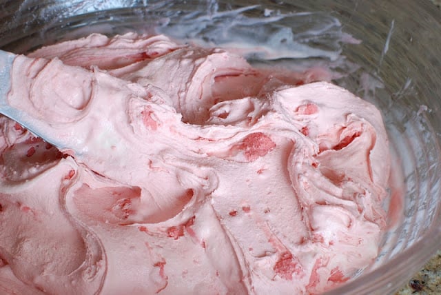 Raspberry sorbet and vanilla ice cream being blended in a bowl.