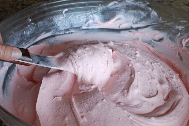 Raspberry sorbet and vanilla ice cream being blended in a bowl.