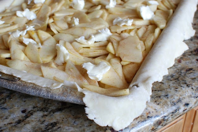 Apples filling in pastry lined pan dotted with butter.