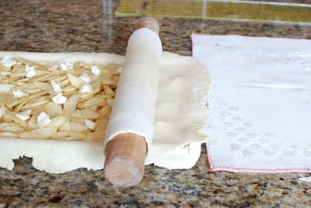 Pie crust dough rolled out over top of sliced apple filling.