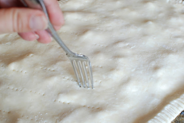 A fork poking air vents into the top of the pie dough.