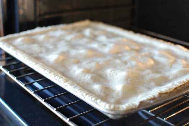 Placing slab apple pie into an oven