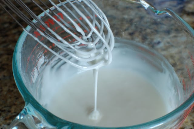 Whisk mixing powdered sugar and milk together.